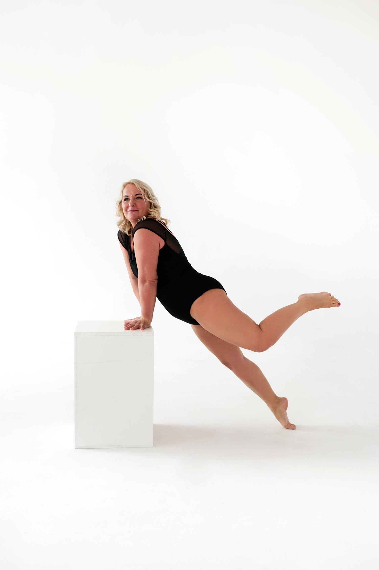 nő fehér háttér előtt támaszkodik egy asztalon